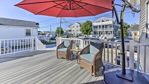 A wooden deck with wicker furniture and a red umbrella. - Charming Wildwood Hideaway w/ Private Pool & Deck! (Wildwood)