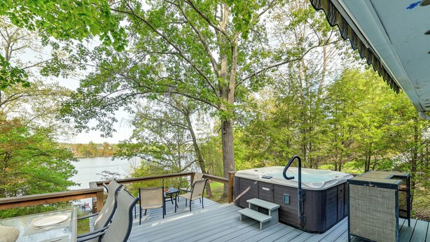 Een terras met een jacuzzi, stoelen en een tafel, met uitzicht op een meer.