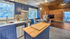 Een moderne keuken met blauwe kastjes, een houten kookeiland en een groot raam.