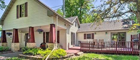A two-story house with a porch, a small deck, and a fenced backyard.