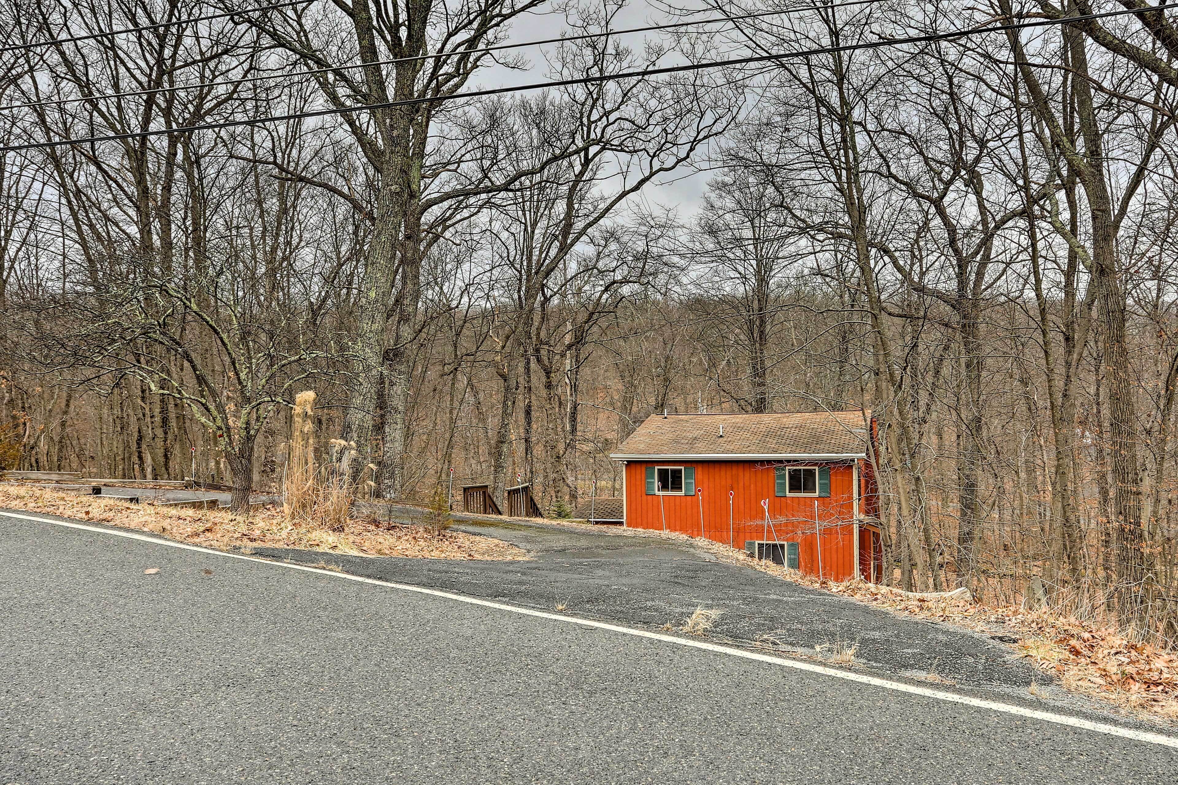 A red building with a sloped roof, surrounded by leafless trees and a paved road.