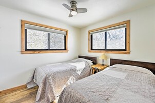Un dormitorio con dos camas, cabeceros de madera y ventanas con persianas.
