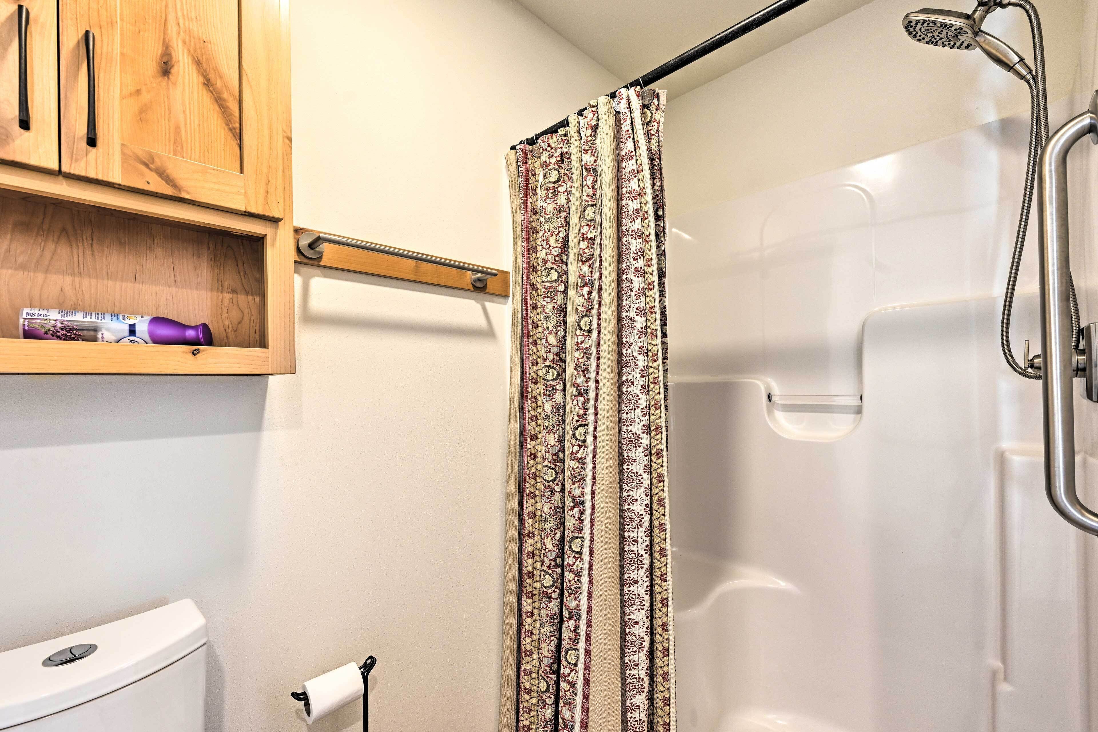 A bathroom with a shower, toilet, and a shelf with toiletries.