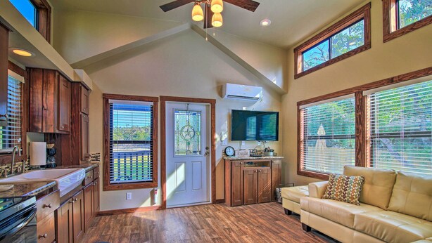 A spacious living area with a large window, a built-in TV, and a wooden floor.