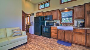 A kitchen with wooden cabinets, a refrigerator, stove, microwave, and a sink.