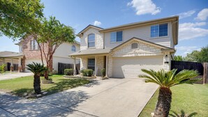 A two-story house with a garage, a covered porch, and a well-maintained lawn with palm trees. - Near Seaworld! Modern Family Home w/ Pool Access (San Antonio)