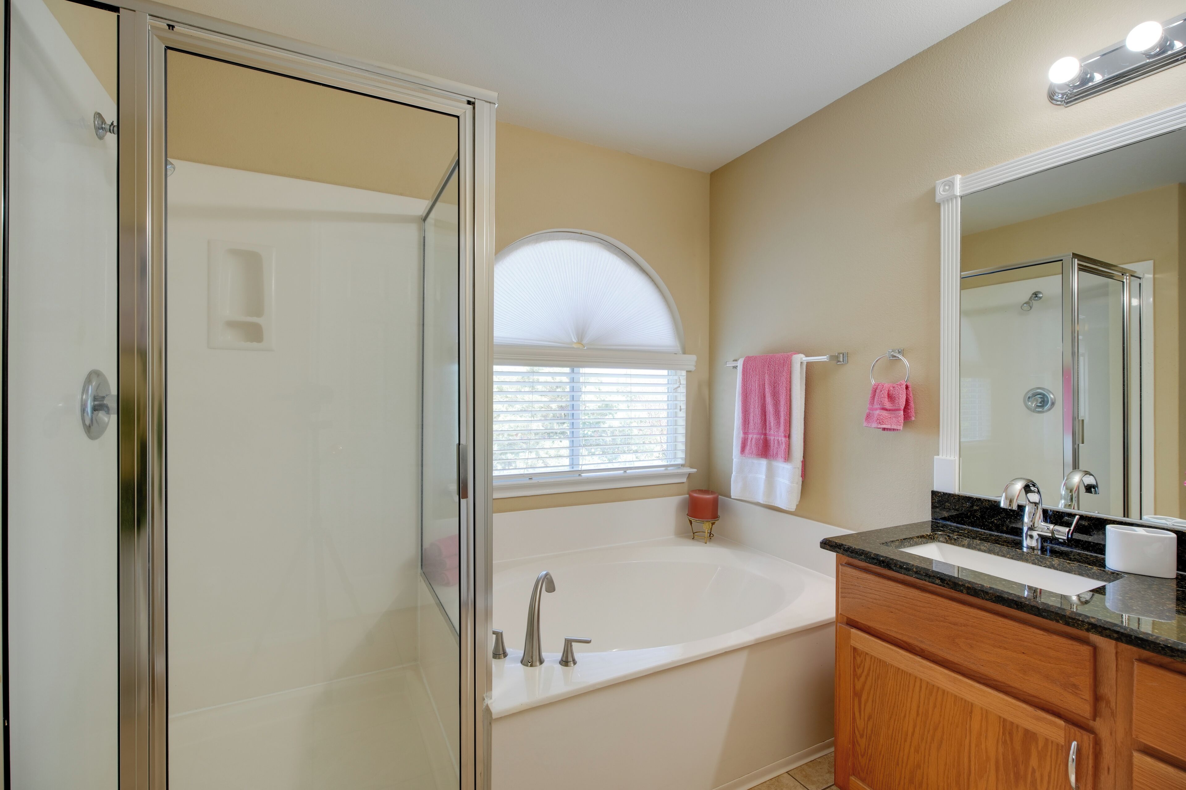 A bathroom with a bathtub, vanity, and a large mirror.