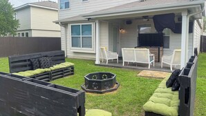 A backyard with a wooden deck, a green cushioned seating area, and a raised garden bed. - Near Seaworld! Modern Family Home w/ Pool Access (San Antonio)