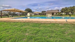 A backyard with a swimming pool, covered patio area, and a house in the background. - Near Seaworld! Modern Family Home w/ Pool Access (San Antonio)