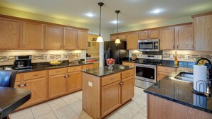 A kitchen with wooden cabinets, a central island, stainless steel appliances, and pendant lighting. - Near Seaworld! Modern Family Home w/ Pool Access (San Antonio)