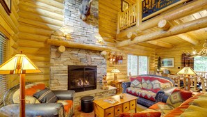 A log cabin interior with a stone fireplace, leather sofas, and a cozy ambiance. - Exquisite Mccall Log Cabin - Walk to Payette Lake! (McCall)