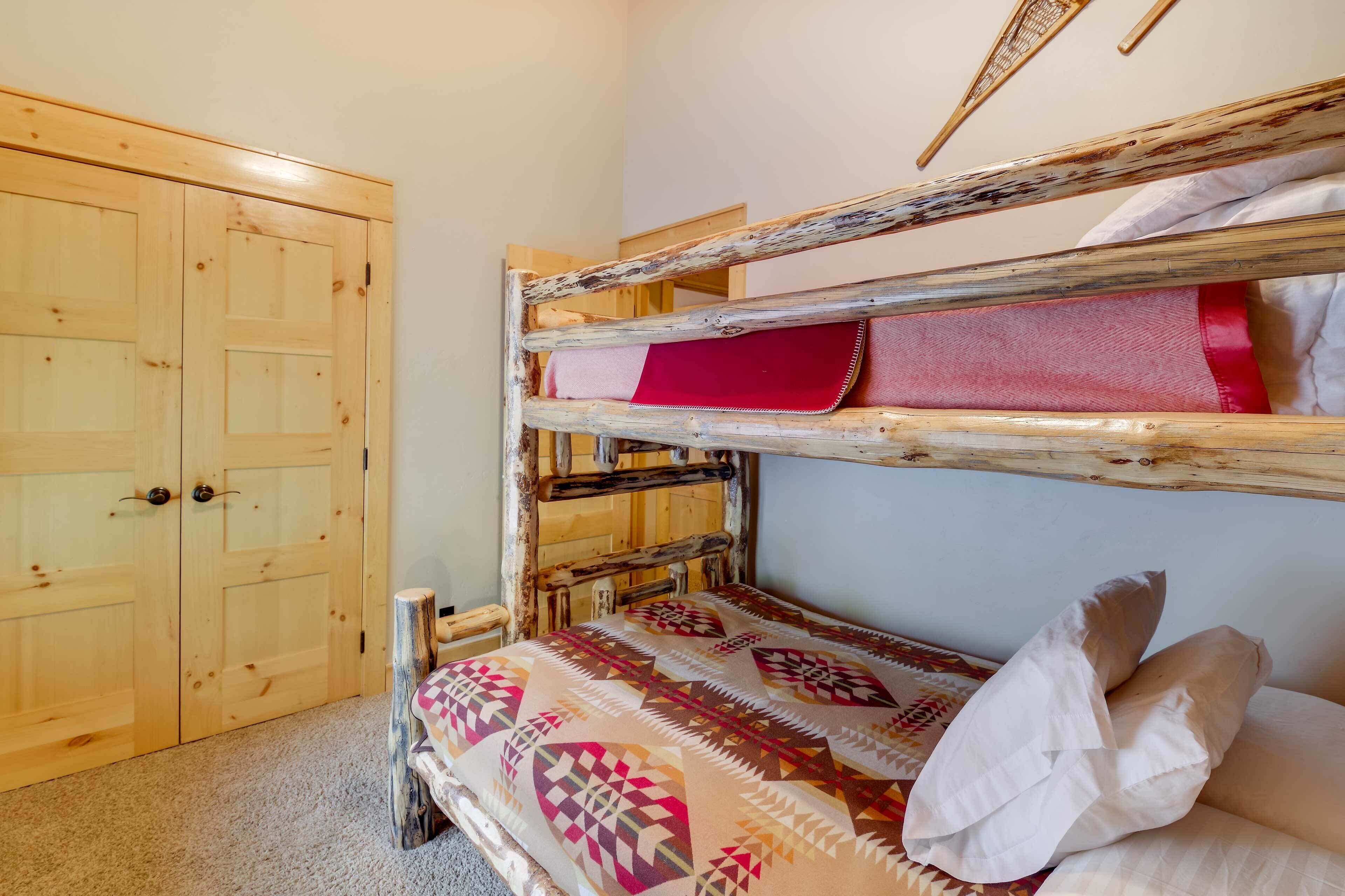 A bunk bed with a patterned bedspread, a wooden wardrobe, and a door with a handle.