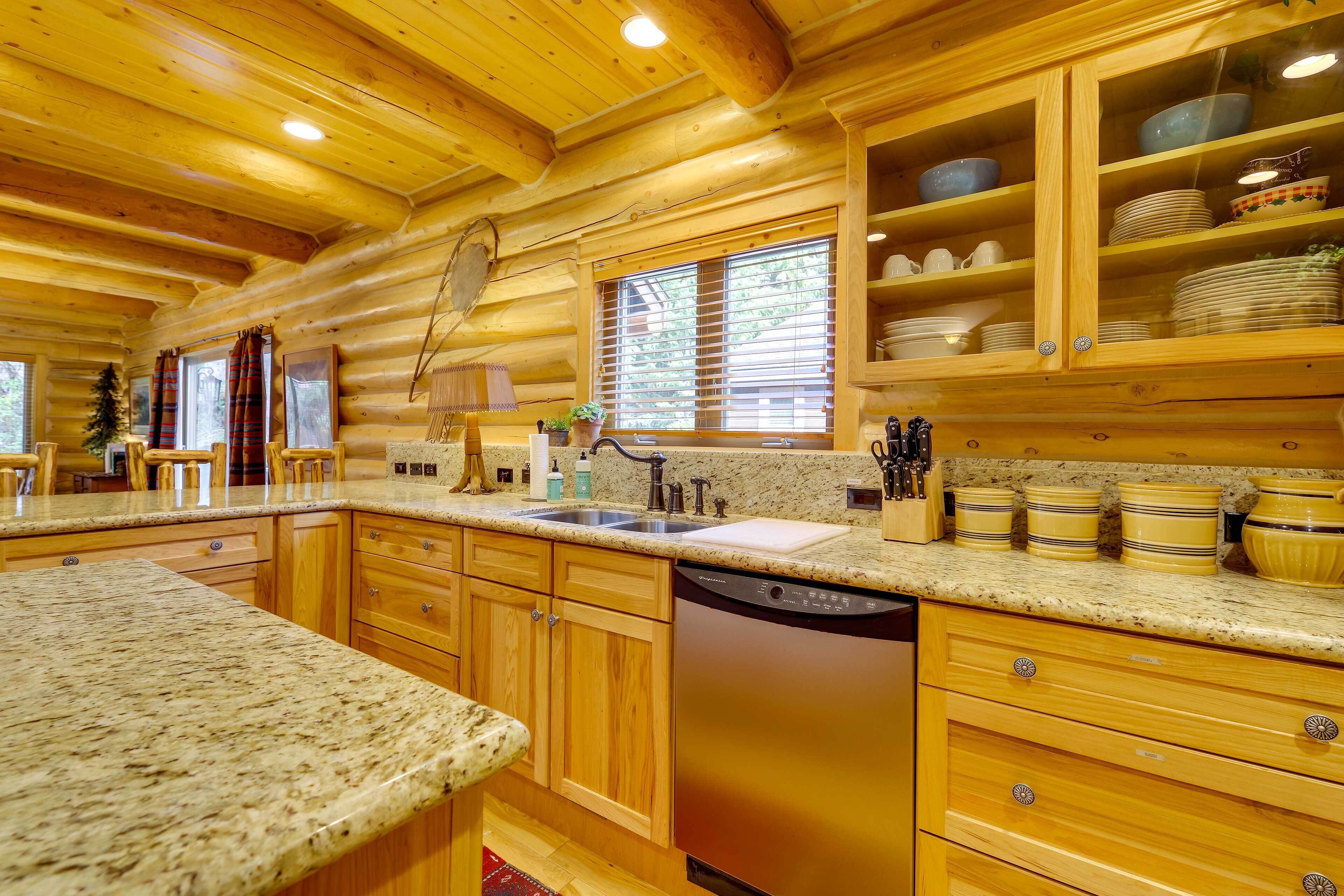 A log cabin kitchen with granite countertops, wooden cabinets, a dishwasher, and a window with blinds.