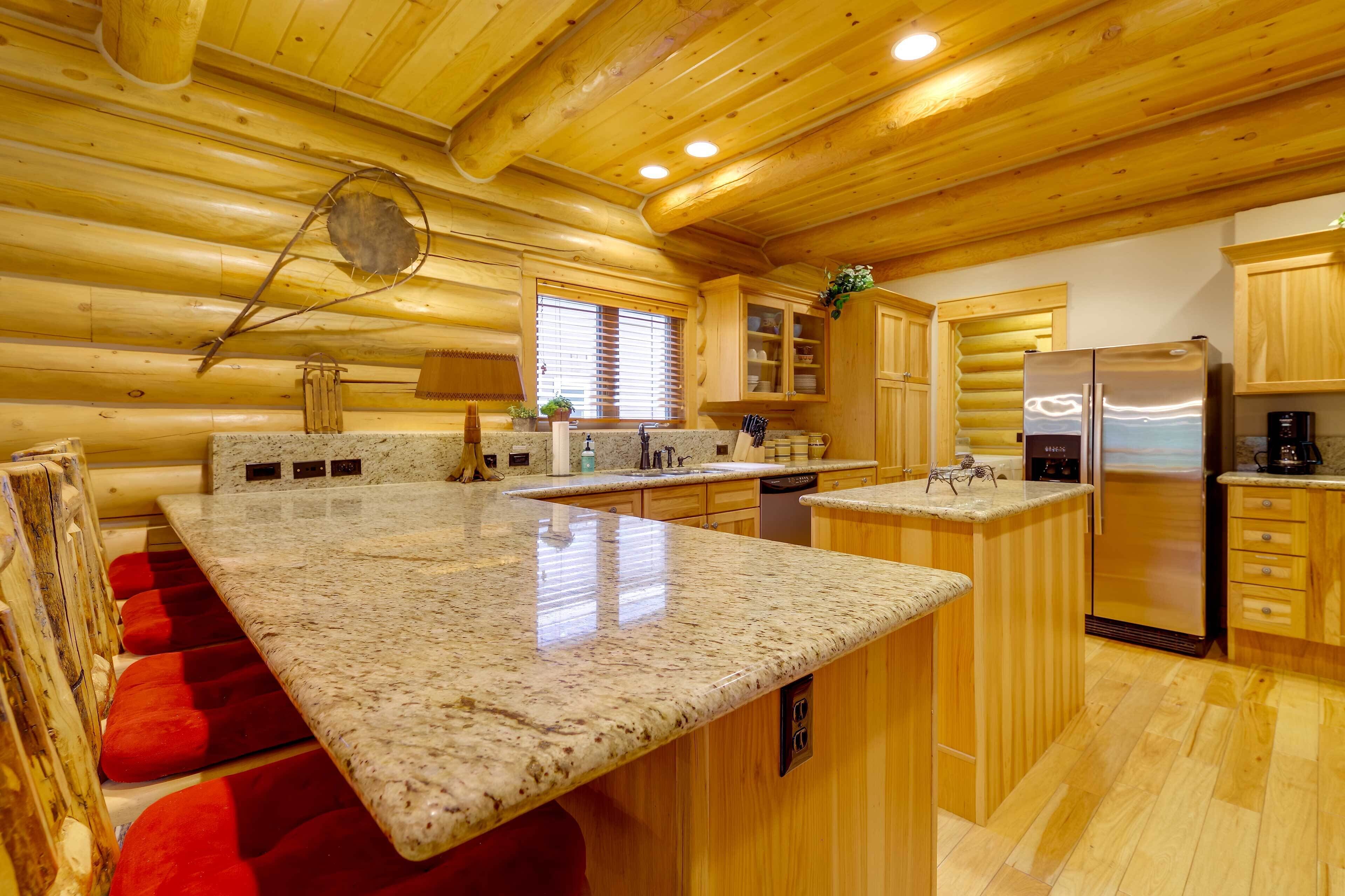 A log cabin kitchen with granite countertops, wooden cabinets, and a stainless steel refrigerator.