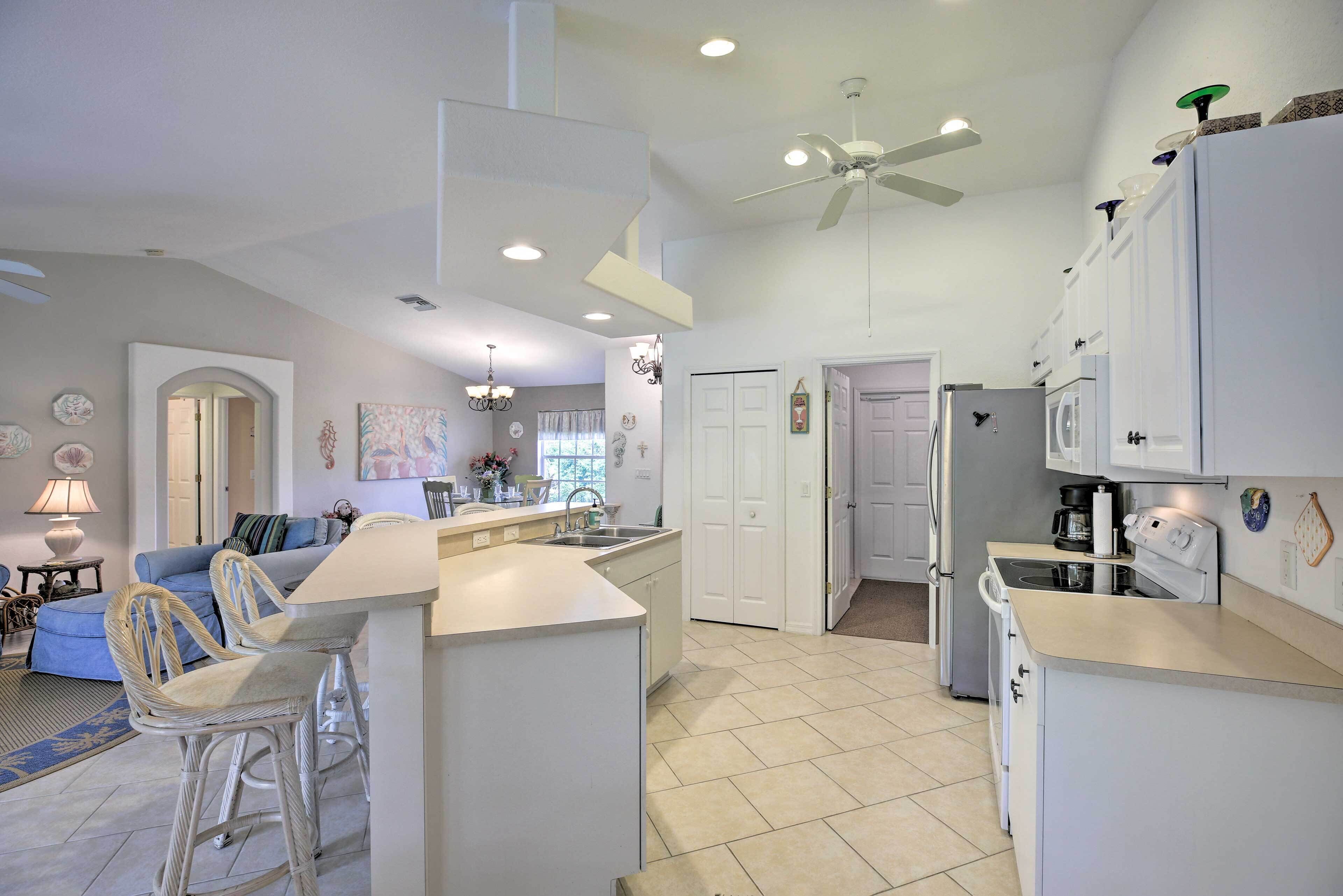 A modern kitchen with white cabinetry, a central island, and a ceiling fan.
