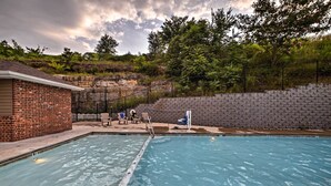 A swimming pool with a brick building and stone wall in the background.