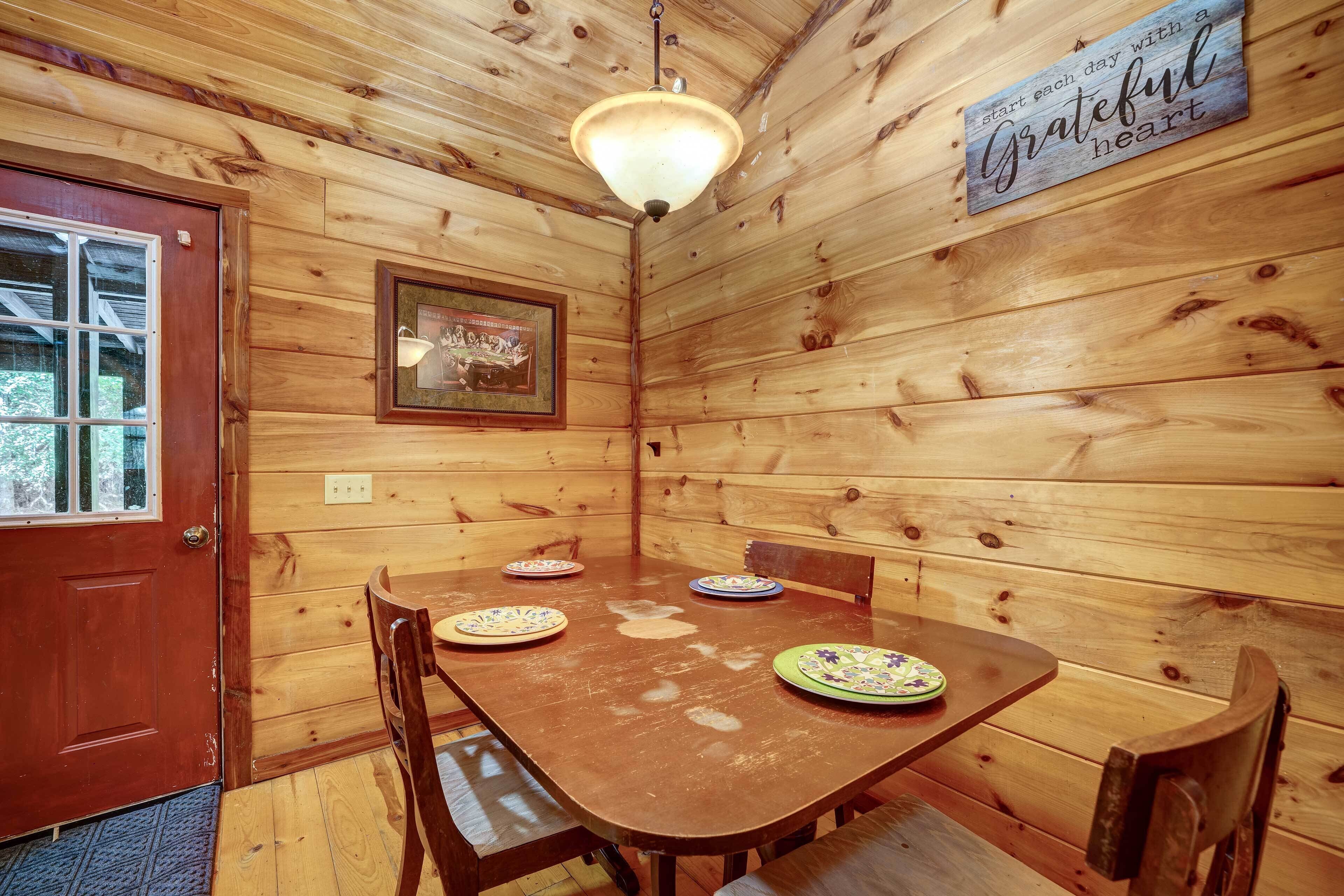 Un comedor de madera con una mesa preparada para cuatro, una puerta de madera y un letrero en la pared.