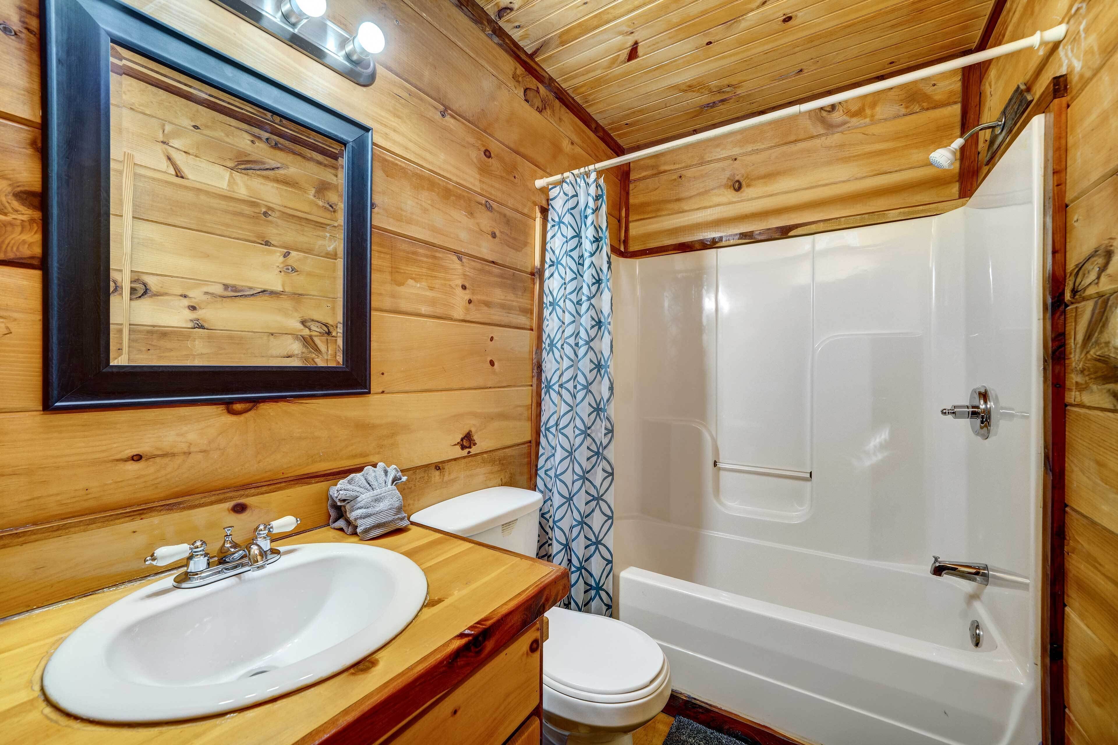 Et badeværelse i en træhytte med vask, toilet og badekar.