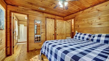 Ein Schlafzimmer in einer Holzhütte mit einem Bett, einem Deckenventilator und Holztüren.