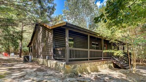 A rustic log cabin with a porch, surrounded by trees. - Private Broken Bow Cabin w/ Hot Tub + Gazebo! (Broken Bow)