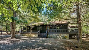 A rustic cabin with a stone foundation, wooden deck, and a small porch. - Private Broken Bow Cabin w/ Hot Tub + Gazebo! (Broken Bow)