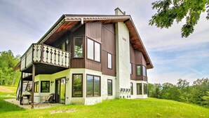 A two-story house with a balcony, large windows, and a grassy yard. - Scenic Bartlett Home w/ Deck - 1 Mi to Storyland! (Glen)