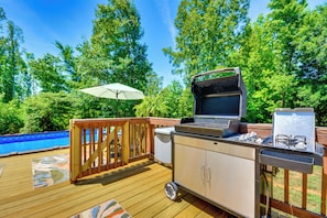 An outdoor deck with a grill, a small refrigerator, and a pool. - Browns Summit Vacation Rental w/ Fire Pit! (Browns Summit)