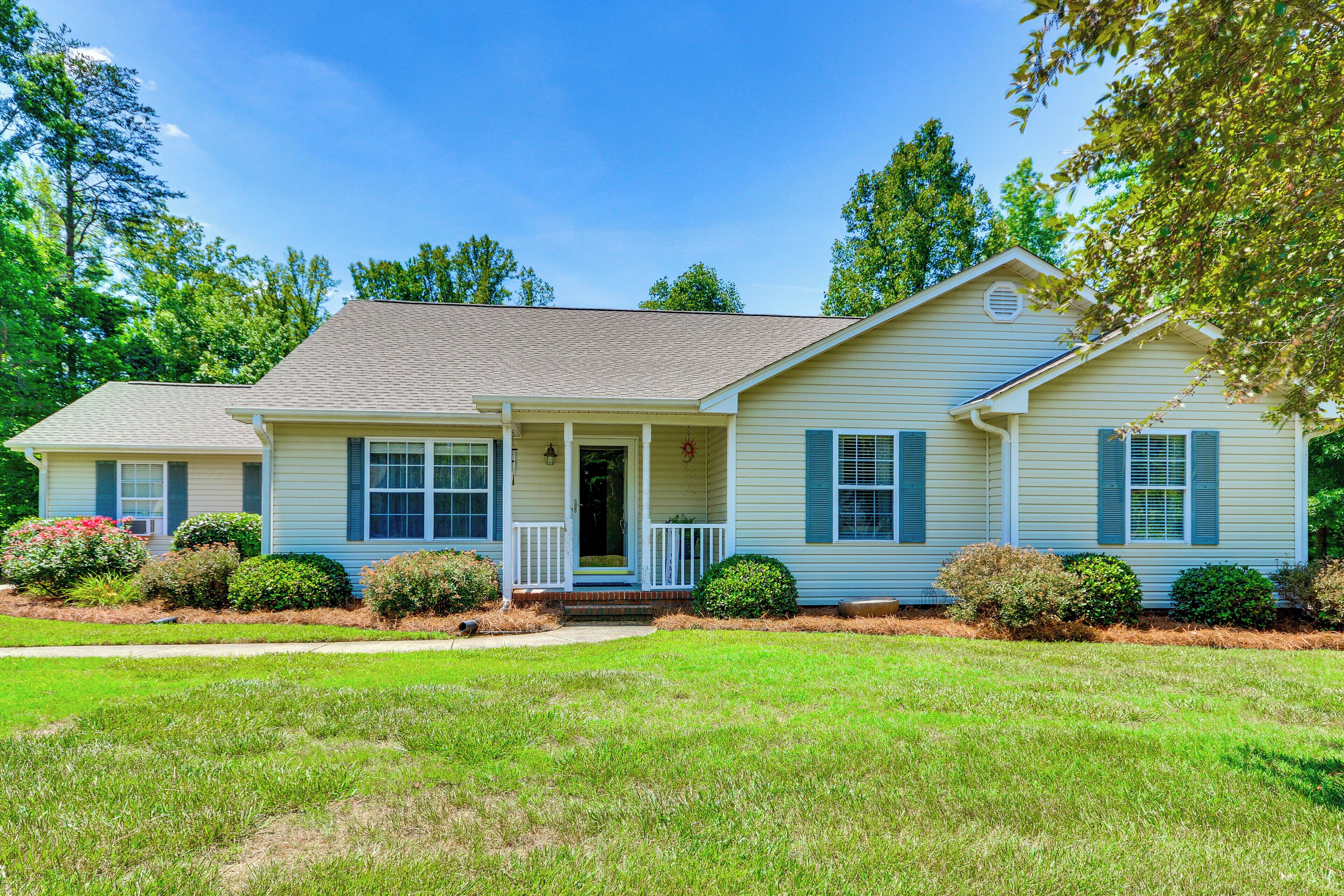 A single-story house with a front porch, a small front yard, and a clear blue sky.