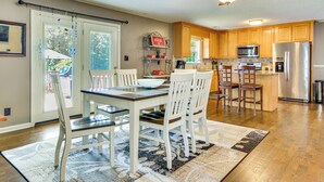 A kitchen with wooden cabinets, a dining table with chairs, a ceiling fan, and a refrigerator. - Browns Summit Vacation Rental w/ Fire Pit! (Browns Summit)