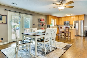 A kitchen with wooden cabinets, a dining table with chairs, a ceiling fan, and a refrigerator. - Browns Summit Vacation Rental w/ Fire Pit! (Browns Summit)