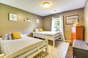 A bedroom with two beds, a dresser, a mirror, and a window with curtains.