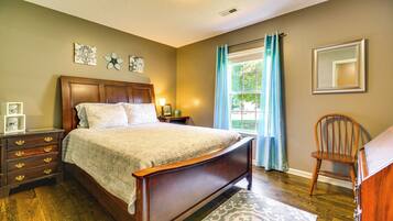 Une chambre à coucher avec un lit en bois, une table de chevet, une commode, une chaise et une fenêtre avec des rideaux.