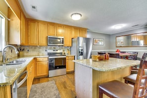 A kitchen with wooden cabinets, stainless steel appliances, granite countertops, and a breakfast bar. - Browns Summit Vacation Rental w/ Fire Pit! (Browns Summit)
