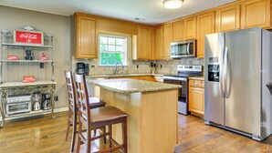 A kitchen with wooden cabinets, a stainless steel refrigerator, a microwave, and a coffee maker. - Browns Summit Vacation Rental w/ Fire Pit! (Browns Summit)