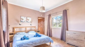 A bedroom with a bed, wooden headboard, a dresser, a window with curtains, and artwork on the wall. - Beautiful villa with private pool and sea view (foupana, moncarapacho)