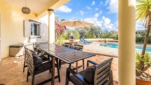 An outdoor patio with a wooden table and chairs, a pool, and a view of the surrounding landscape. - Beautiful villa with private pool and sea view (foupana, moncarapacho)
