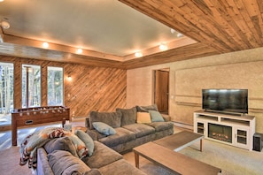 Un salon chaleureux avec un plafond en bois, un grand canapé, un téléviseur et une cheminée.