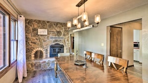 A dining area with a long wooden table, stone walls, and a fireplace. - Charming Leadville Retreat w/ Private Hot Tub (Leadville)