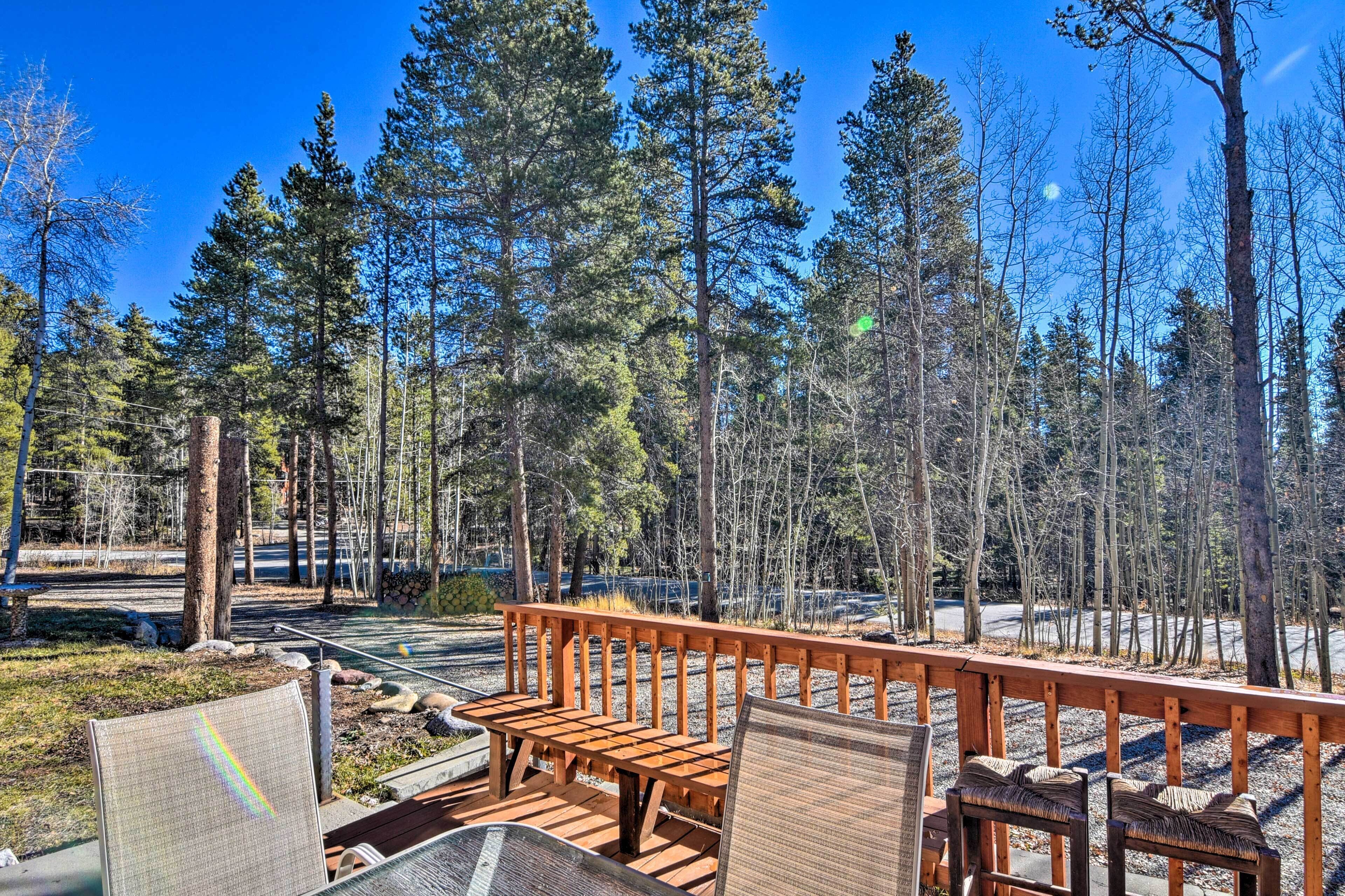 A wooden deck with benches and a railing overlooking a forested area.
