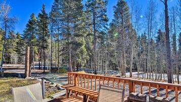 A wooden deck with benches and a railing overlooking a forested area.