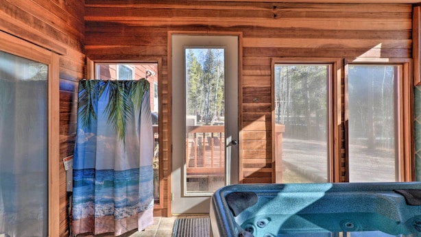 A wooden cabin with a hot tub, large windows, and a door leading outside. - Charming Leadville Retreat w/ Private Hot Tub (Leadville)