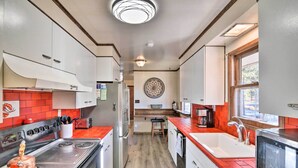 A compact kitchen with a stove, sink, and refrigerator, featuring a wooden floor and red accents. - Charming Leadville Retreat w/ Private Hot Tub (Leadville)