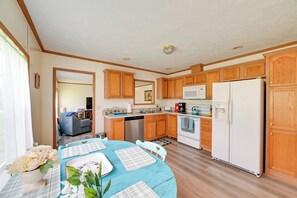 A kitchen with wooden cabinets, a white refrigerator, a microwave, and a dishwasher. - Warm & Inviting Family Home - 2 Mi to Golf Course! (McEwen)