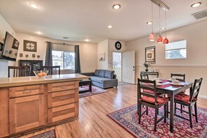 A spacious living area with a kitchen, dining table, and a grey sofa.
