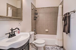 A bathroom with a sink, toilet, bathtub, and shower curtain.