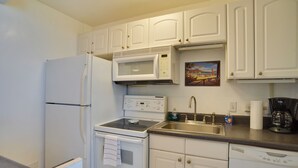 A kitchen with white cabinets, a microwave, stove, sink, and dishwasher. - Oceanfront Lahaina Condo w/ Balcony & Pool Access! (Napili-Honokowai)