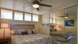 A bedroom with a bed, nightstands, a dresser, a ceiling fan, and a large mirror. - Oceanfront Lahaina Condo w/ Balcony & Pool Access! (Napili-Honokowai)