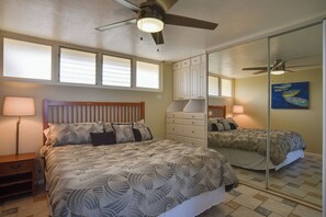 Una camera da letto con un letto, comodini, una cassettiera, una ventola a soffitto e uno specchio grande.