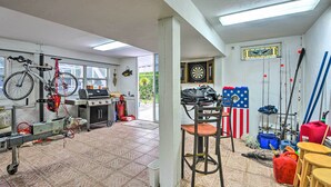 Un garage con una bicicletta, un barbecue, canne da pesca e diversi attrezzi.