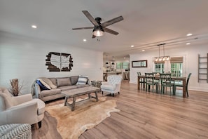 A spacious living room with a large sofa, a coffee table, and a dining area with a wooden table and chairs. - Chic Urban Farmhouse in Historic Dilworth w/ Patio (Charlotte)